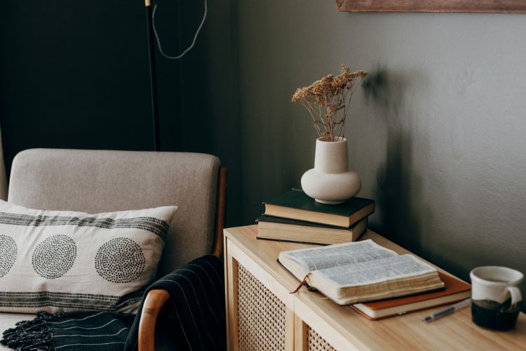 casa minimalista e funcional, imagem de uma estante com livros, café e ao lado uma poltrona aconchegante